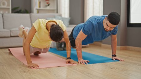 Photo for Beautiful couple showcasing power and love, training together with indoor push up workout at home - Royalty Free Image