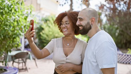 Téléchargez les photos : Beau couple souriant, debout ensemble dans le parc, profitant de plaisir selfie en plein air avec smartphone - en image libre de droit