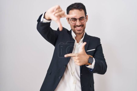 Téléchargez les photos : Beau homme d'affaires hispanique debout sur fond blanc souriant faisant cadre avec les mains et les doigts avec le visage heureux. concept de créativité et photographie. - en image libre de droit