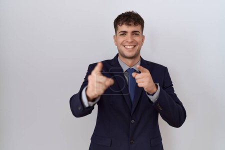 Téléchargez les photos : Jeune homme d'affaires hispanique portant costume et cravate pointant les doigts vers la caméra avec un visage heureux et drôle. bonne énergie et vibes. - en image libre de droit