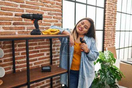 Photo for Young beautiful plus size woman smiling confident repairing shelving at new home - Royalty Free Image