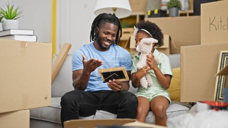 Photo for African american father and daughter unpacking cardboard box at new home - Royalty Free Image