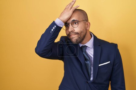 Photo for Hispanic man with beard wearing suit and tie surprised with hand on head for mistake, remember error. forgot, bad memory concept. - Royalty Free Image