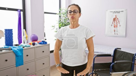 Photo for Mature hispanic woman doing breathing exercises in a well-equipped rehabilitation clinic - Royalty Free Image