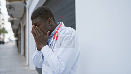 Foto de Médico afroamericano sintiéndose estresado en una calle de la ciudad - Imagen libre de derechos