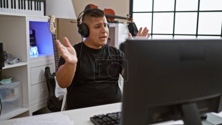 Photo for Passionate young latin musician man immersed in an energetic musical performance, skillfully using computer and headphones at his music studio, channeling his artistry indoors - Royalty Free Image