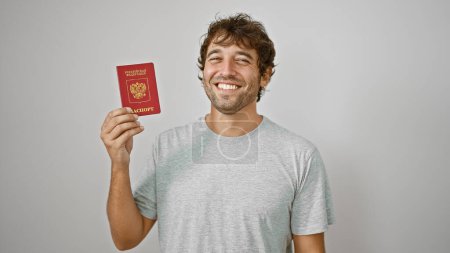 Téléchargez les photos : Jeune homme blond rayonnant, patriote de Russie, détient un passeport avec confiance sur fond blanc isolé, prêt à profiter de son voyage de vacances - en image libre de droit