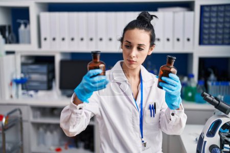 Téléchargez les photos : Young caucasian woman scientist holding bottles at laboratory - en image libre de droit