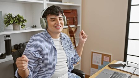 Foto de Joven disfruta de la música con auriculares mientras toma un descanso en una oficina moderna. - Imagen libre de derechos