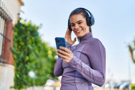 Téléchargez les photos : Young beautiful hispanic woman wearing sportswear listening to music at street - en image libre de droit