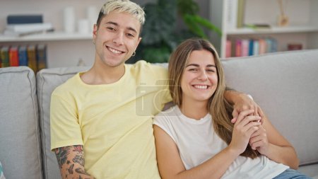 Photo for Beautiful couple hugging each other sitting on sofa at home - Royalty Free Image