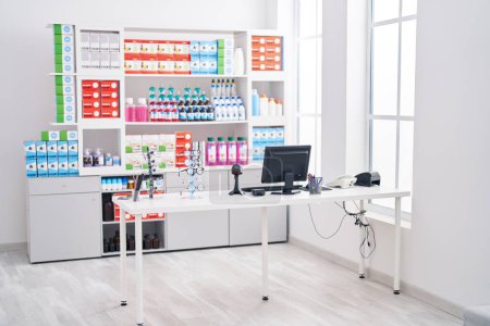 Foto de Interior de la farmacia moderna con estantes de la medicina, computadora, anteojos, y contador bajo iluminación brillante - Imagen libre de derechos