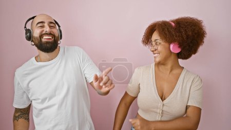 Foto de Hermosa pareja, llena de amor, disfrutando de un baile juntos mientras escuchan música, sobre un fondo rosa aislado - Imagen libre de derechos