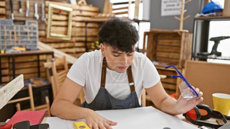 Foto de Un joven en un taller centrado en un proyecto de carpintería creativa en el interior, encarnando la artesanía y la atención al detalle. - Imagen libre de derechos