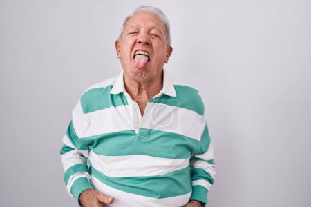 Photo for Senior man with grey hair standing over white background sticking tongue out happy with funny expression. emotion concept. - Royalty Free Image