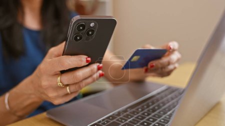 Téléchargez les photos : Une femme d'affaires effectue un paiement en ligne sécurisé avec sa carte de crédit et son smartphone dans son espace de travail moderne. - en image libre de droit