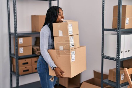Téléchargez les photos : African american woman ecommerce business worker holding packages at office - en image libre de droit