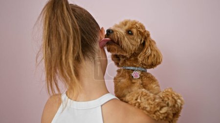 Photo for Young caucasian woman with dog kissing ear over isolated pink background - Royalty Free Image