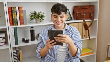 Foto de Joven sonriente con una tableta en una oficina moderna, mostrando atuendo de trabajo casual y uso de la tecnología. - Imagen libre de derechos