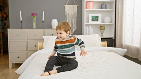 Photo for A cheerful toddler boy playing on a white bed in a cozy, modern bedroom setting, embodying childhood innocence. - Royalty Free Image