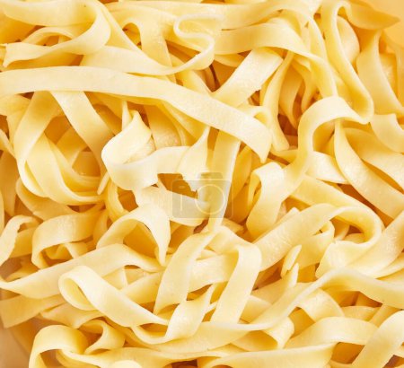 Téléchargez les photos : Gros plan sur les pâtes fettuccine fraîches à l'aspect texturé, doré et appétissant, révélateur de la cuisine italienne. - en image libre de droit