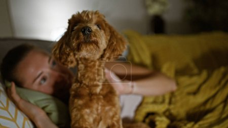 Foto de Joven mujer caucásica con perro jugando acostado en el sofá en casa - Imagen libre de derechos
