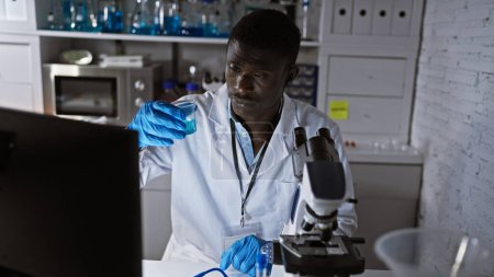 Téléchargez les photos : Un homme scientifique africain analyse un liquide en laboratoire - en image libre de droit