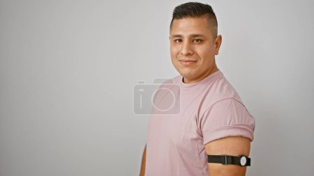 Photo for Vibrant portrait of a confident young latin man, smiling comfortably with his freestyle diabetes sensor, isolated against a white background - Royalty Free Image