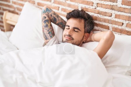 Joven hispano acostado en la cama durmiendo en el dormitorio