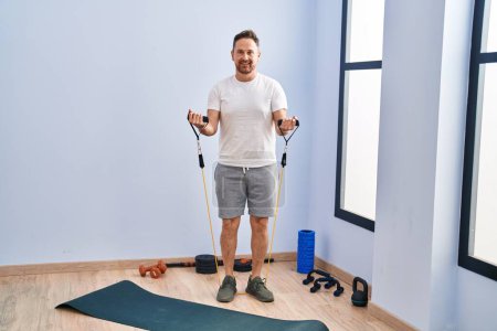 Photo for Young caucasian man smiling confident using elastic band training at sport center - Royalty Free Image
