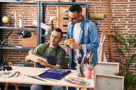 Téléchargez les photos : Deux artistes hommes dessinant sur ordinateur portable buvant du café au studio d'art - en image libre de droit