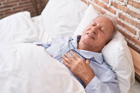 Hombre de pelo gris de mediana edad acostado en la cama durmiendo en el dormitorio