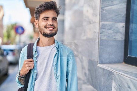 Photo for Young hispanic man student smiling confident wearing backpack at street - Royalty Free Image