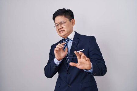 Photo for Young asian man wearing business suit and tie disgusted expression, displeased and fearful doing disgust face because aversion reaction. - Royalty Free Image
