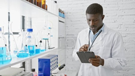 Foto de Hombre científico africano analizando datos en una tableta en un entorno de laboratorio brillante. - Imagen libre de derechos