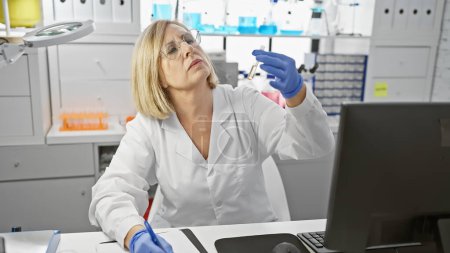 Foto de Científica de mediana edad examinando un tubo de ensayo en un laboratorio de interior, retratando profesionalidad y concentración. - Imagen libre de derechos