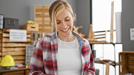 Photo for Smiling blonde woman wearing plaid in a woodworking workshop indoors - Royalty Free Image