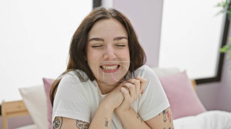 Téléchargez les photos : Une jeune femme caucasienne joyeuse avec des tatouages profitant d'un moment dans sa chambre confortable - en image libre de droit