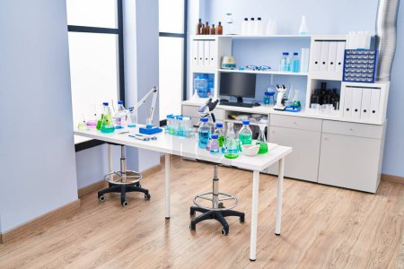 Foto de Moderno interior de laboratorio con equipo de investigación científica en el escritorio y estantes llenos de archivos y botellas. - Imagen libre de derechos