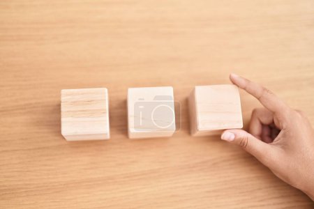 Photo for Young beautiful hispanic woman business worker sitting on table with wooden cubes at office - Royalty Free Image