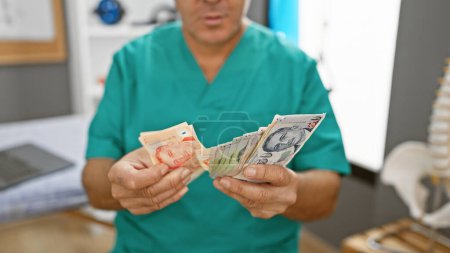Foto de Un hombre de mediana edad con uniforme cuenta dólares singapurenses en el interior de una clínica médica. - Imagen libre de derechos
