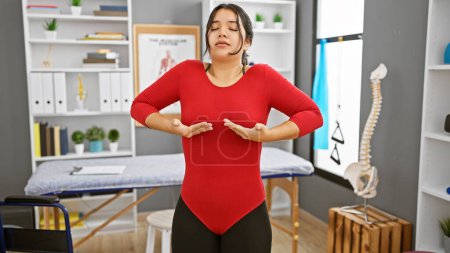 Téléchargez les photos : Femme hispanique pratiquant des exercices respiratoires dans la salle de thérapie d'une clinique de réadaptation, mettant en valeur la santé et le bien-être. - en image libre de droit