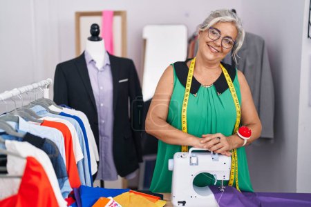 Photo for Middle age grey-haired woman tailor smiling confident standing at tailor shop - Royalty Free Image
