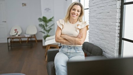 Téléchargez les photos : Jeune femme blonde femme d'affaires souriant confiant assis avec les bras croisés geste au bureau - en image libre de droit