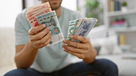 Dynamischer junger Mann, der Geld verdient, gemütlich zu Hause auf dem Sofa sitzt und einen Blick in die chinesische Wirtschaft wirft