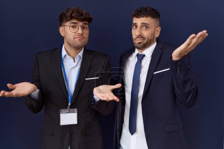 Photo for Two hispanic business men wearing business clothes clueless and confused expression with arms and hands raised. doubt concept. - Royalty Free Image