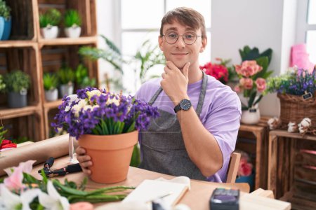 Photo for Caucasian blond man working at florist shop looking confident at the camera smiling with crossed arms and hand raised on chin. thinking positive. - Royalty Free Image