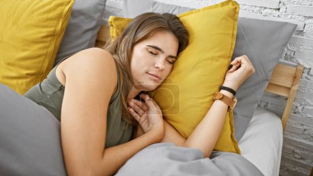 Photo for Young, beautiful hispanic woman fast asleep under a cozy blanket, lying fully relaxed in the comfort of her home bedroom - Royalty Free Image