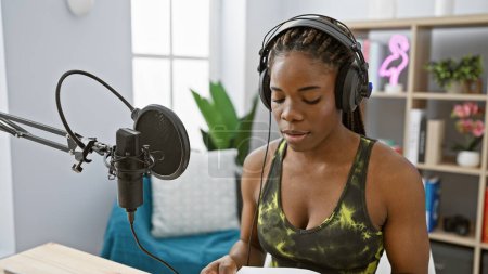 Foto de Una mujer afroamericana con trenzas se dedica a transmitir en un estudio de radio interior - Imagen libre de derechos