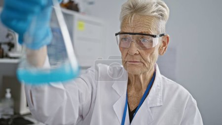 Téléchargez les photos : Femme scientifique chevelue travaillant et mesurant des liquides dans des éprouvettes en laboratoire intérieur, assurant méticuleusement la sécurité et la précision dans la recherche médicale - en image libre de droit